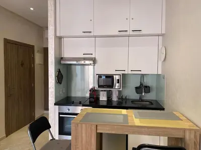 a kitchen with white cabinets and a table with chairs at Nid douillet à Gueliz in Marrakech
