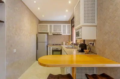 a kitchen with a table and a refrigerator at Le Palmier - Appartement Authentique à Gueliz in Marrakech