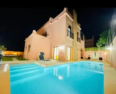 a swimming pool in front of a house at night at The Villa avec piscine chauffée 4 chambres in Marrakech