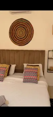 a bed with pillows and a decoration on the wall at Riad Laila Marrakech in Marrakech