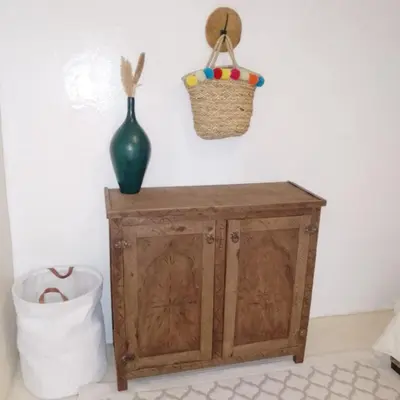 a wooden cabinet with a vase and a basket on a wall at Riad Laila Marrakech in Marrakech