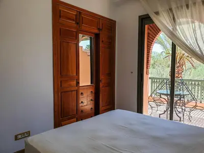 a bedroom with a bed and a door to a balcony at palmeraie village 2 in Marrakech
