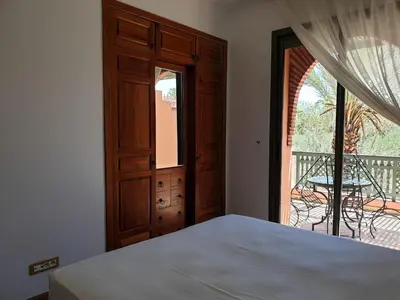a bedroom with a bed and a door to a balcony at palmeraie village 2 in Marrakech
