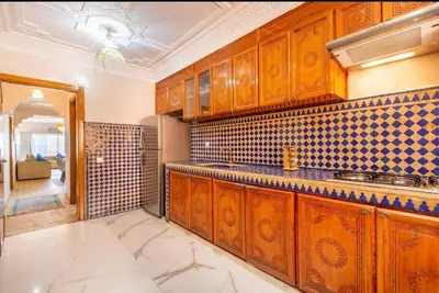 a kitchen with wooden cabinets and tiles on the wall at Luxury Appartement gueliz center in Marrakech