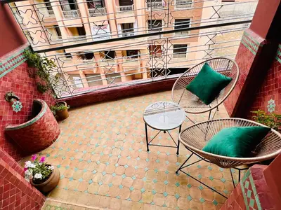 a patio with two chairs and a table with a green pillow at Luxury Appartement gueliz center in Marrakech