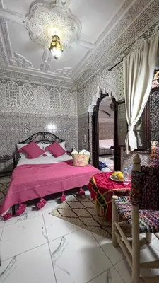 a bedroom with a large bed with a pink blanket at Riad Hayat in Marrakech