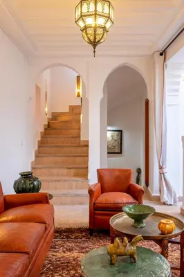 a living room with a couch and a table and stairs at Riad Thé d'Orient - Piscine Privée - Petit Déjeuner in Marrakech