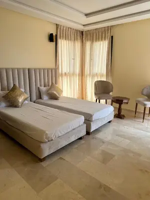 a bedroom with two beds and a chair and a window at Villa avec pool privé avenue Mohamed 6 zone touristique Agdal in Marrakech