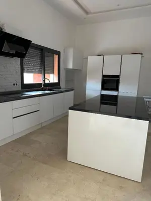 a kitchen with white cabinets and a black counter top at Villa avec pool privé avenue Mohamed 6 zone touristique Agdal in Marrakech