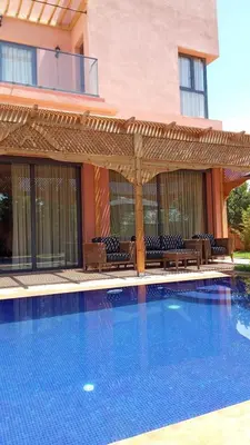 a swimming pool with a pergola next to a building at Villa avec pool privé avenue Mohamed 6 zone touristique Agdal in Marrakech