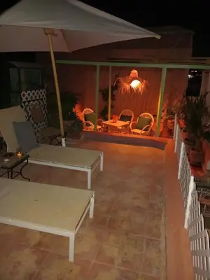 a patio with tables and chairs and an umbrella at Riad El Badii chambre twin Bahia in Marrakech