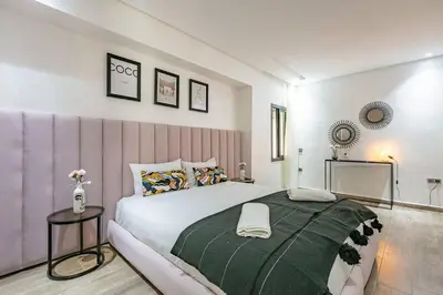 a bedroom with a large bed with a green blanket at Duplex Design, Terrasse résidence Menara garden in Marrakech