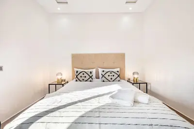 a white bedroom with a large bed with two night stands at Duplex Design, Terrasse résidence Menara garden in Marrakech