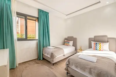 two beds in a room with green curtains and a window at Duplex Design, Terrasse résidence Menara garden in Marrakech