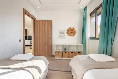 a bedroom with two beds and a door to a kitchen at Duplex Design, Terrasse résidence Menara garden in Marrakech