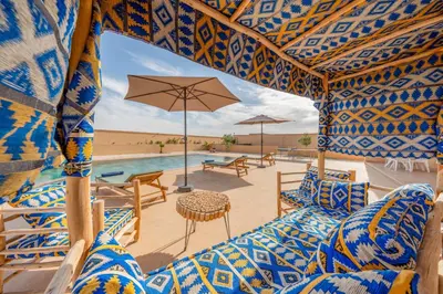 a patio with chairs and an umbrella and a pool at Le Palais de l Atlas luxury villa Marrakech in Douar Ouled Ahmed