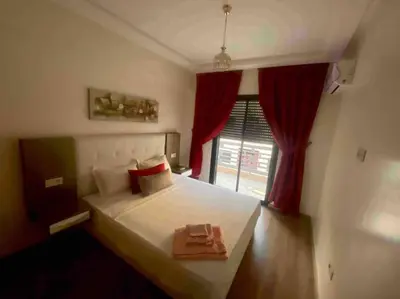 a bedroom with a large white bed with red curtains at Appartement de Haut Standing. in Marrakech