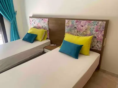 two beds in a room with yellow and blue pillows at Appartement de Haut Standing. in Marrakech