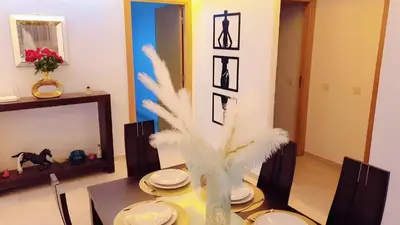 a dining room with a table and a vase with feathers at Appartement de Haut Standing. in Marrakech