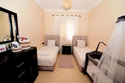 a room with two beds and a dresser and a mirror at KECHDAYS, Lovely apartment near airport in Marrakech