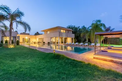 a large house with a swimming pool in front of it at Villa Tomazo Marrakech in Marrakech