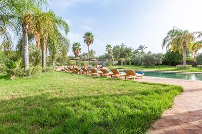 a row of lounge chairs next to a swimming pool at Villa Tomazo Marrakech in Marrakech
