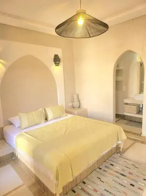 a bedroom with a large bed and a bathroom at Riad Isahiac avec piscine en exclusivité in Marrakech