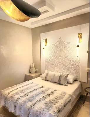 a bedroom with a bed with a white comforter at Riad Isahiac avec piscine en exclusivité in Marrakech