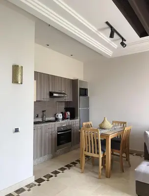 a kitchen with a table and chairs in a room at Vizir Center Appartement avec solarium in Dar Caïd Layadi