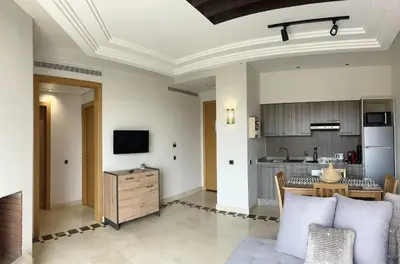 a living room with a table and a kitchen at Vizir Center Appartement avec solarium in Dar Caïd Layadi