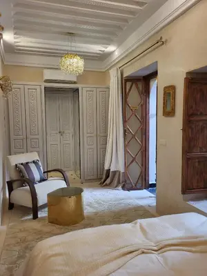 a bedroom with a bed and a couch and a chandelier at Riad LallaBaya in Marrakech
