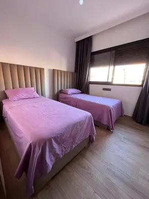 a bedroom with two beds with pink sheets and a window at appartement 2chambres salon Nour8 in Marrakech