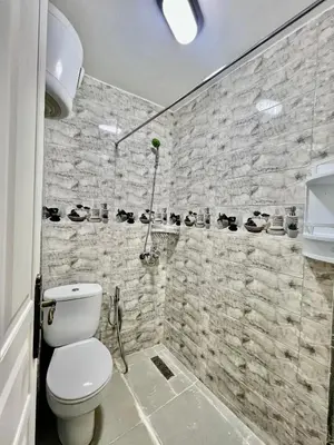 a bathroom with a toilet and a stone wall at Al Hanae Family Aparts in Marrakech