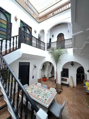 a white house with a table and chairs at Riad Darna 4 chambres avec piscine et petit déjeuner in Marrakech