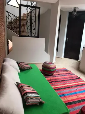 a living room with a green rug and pillows at Riad Baroud in Marrakech