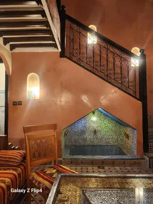 a room with a fireplace and a staircase and a bed at Riad Izza in Marrakech