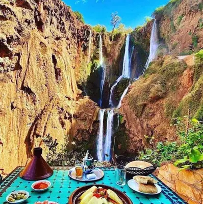 a table with plates of food in front of a waterfall at Riad Izza in Marrakech