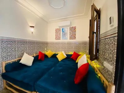a blue couch with colorful pillows in a room at Private Riad 3ch Salon, Terrasse avec Jacuzzi , à Jemaa El Fna in Marrakech