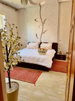 a bedroom with a bed with a tree on the wall at Appartement Marrakech avec piscine privée in Marrakech