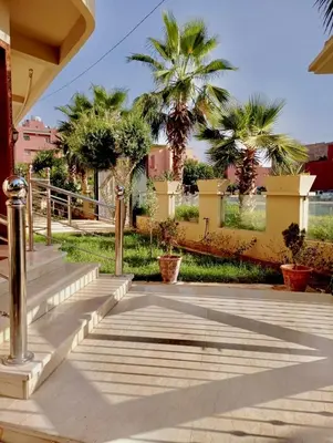 a walkway with palm trees and a fence at Appartement Marrakech avec piscine privée in Marrakech