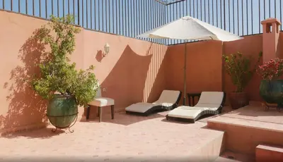 a patio with chairs and an umbrella and a table at Riad Dar Lilas in Marrakech