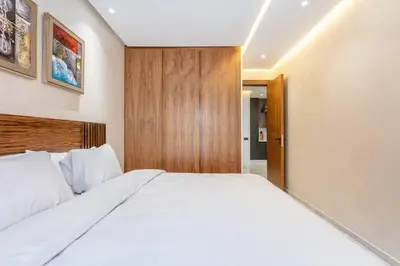 a bedroom with a large white bed with a wooden headboard at Peaceful Living: Chic Apartment, Prime Location in Marrakech