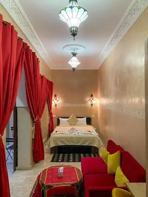 a bedroom with a bed and a red couch at Riad La Bigarade in Marrakech