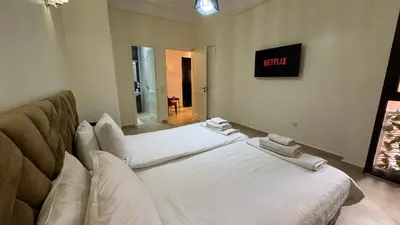 two beds in a room with a clock on the wall at Magnifique Appartement Marrakech - 2 Chambre 2 Salle de Bains in Marrakech