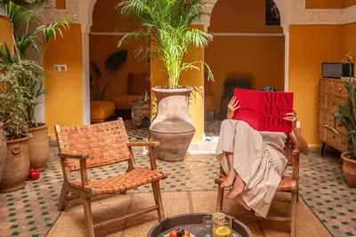 a person sitting in chairs holding a sign that reads way my house at Riad Le Petit Bacha in Marrakech