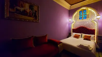 a bedroom with a bed and a chair and a painting at Riad Safir Marrakech in Marrakech