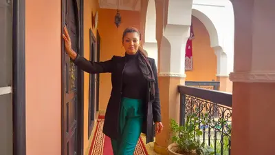 a woman standing on a balcony in a building at Riad Safir Marrakech in Marrakech