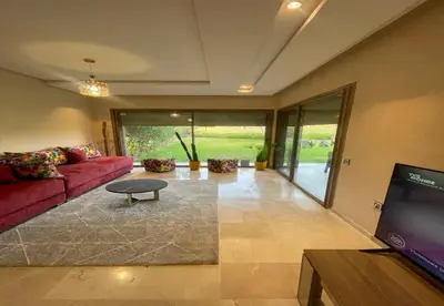 a living room with a red couch and a tv at Appartement Prestigia Golf City Marrakech - Porte Agate - Gated community Rez-de-Jardin in Marrakech