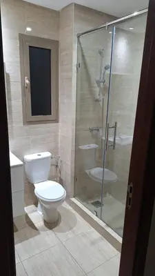 a bathroom with a toilet and a glass shower at Appartement Prestigia Golf City Marrakech - Porte Agate - Gated community Rez-de-Jardin in Marrakech
