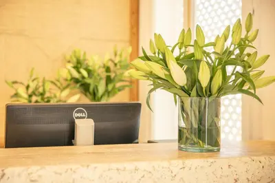 a vase of flowers sitting on a table next to a computer at Les Palmiers Boutique Hôtel & Spa in Marrakech